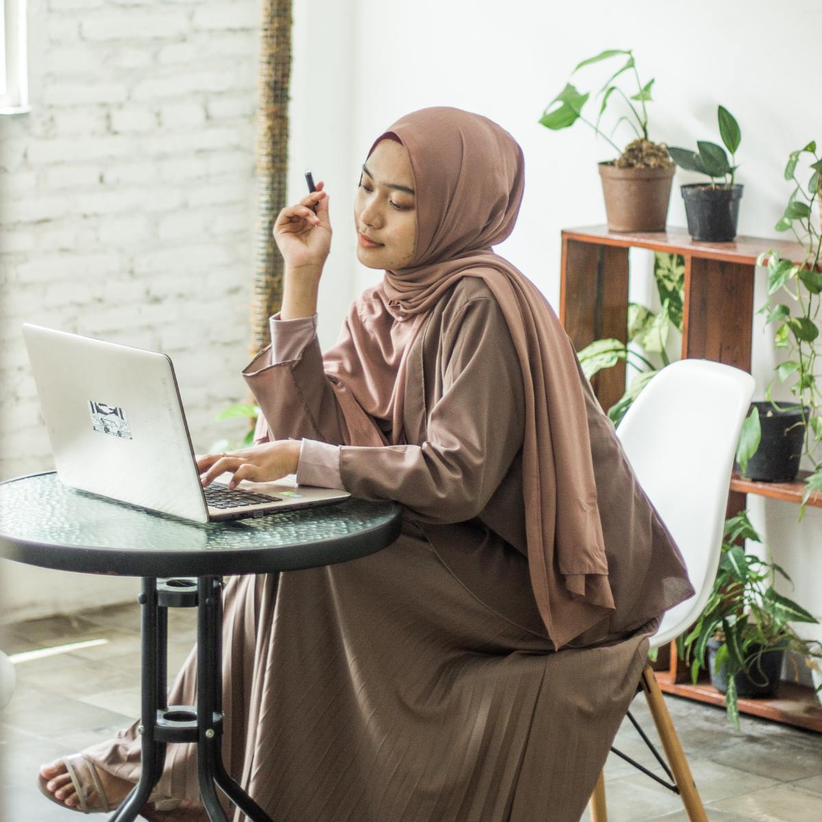 Woman using laptop wearing hijab.