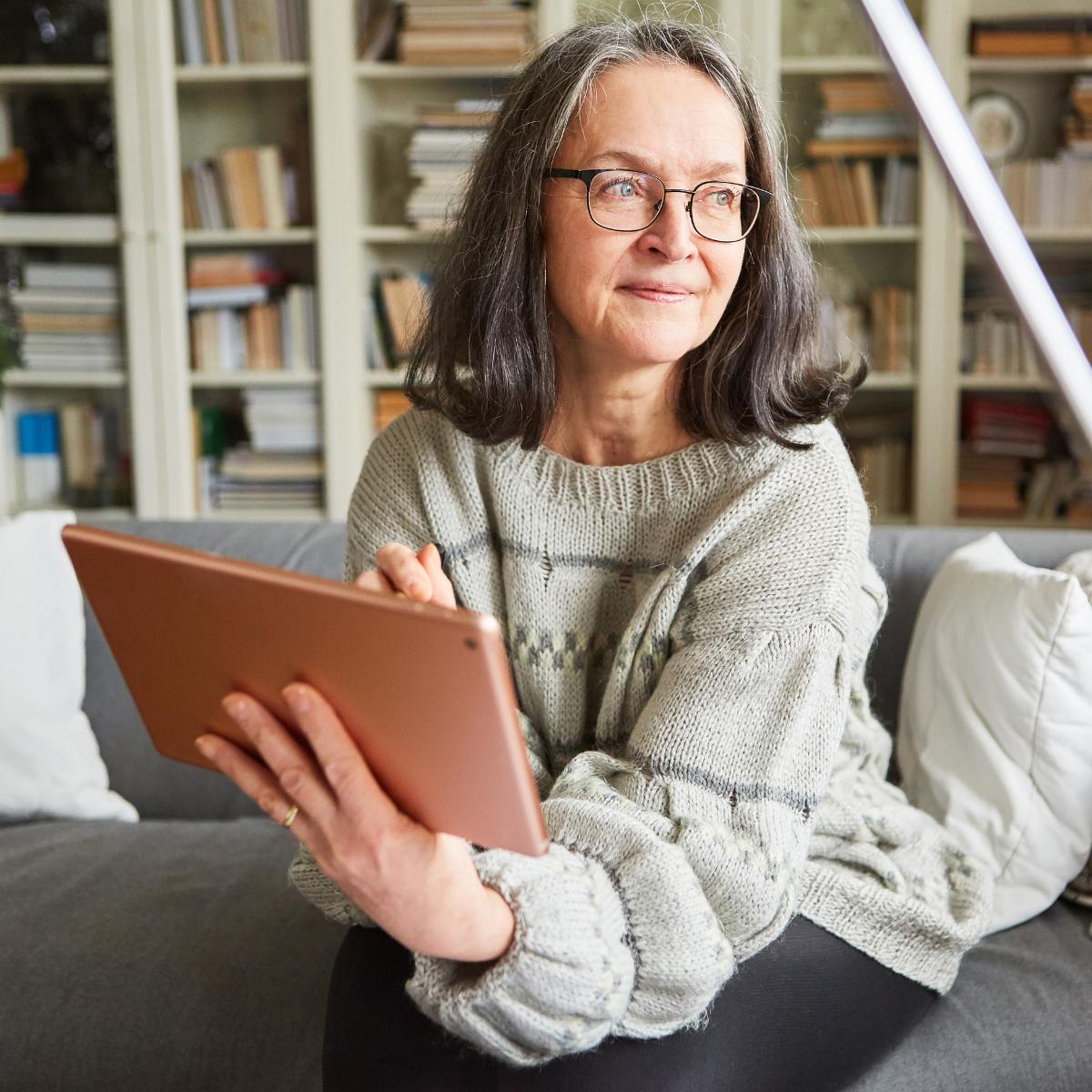 Woman sitting on couch using ipad.