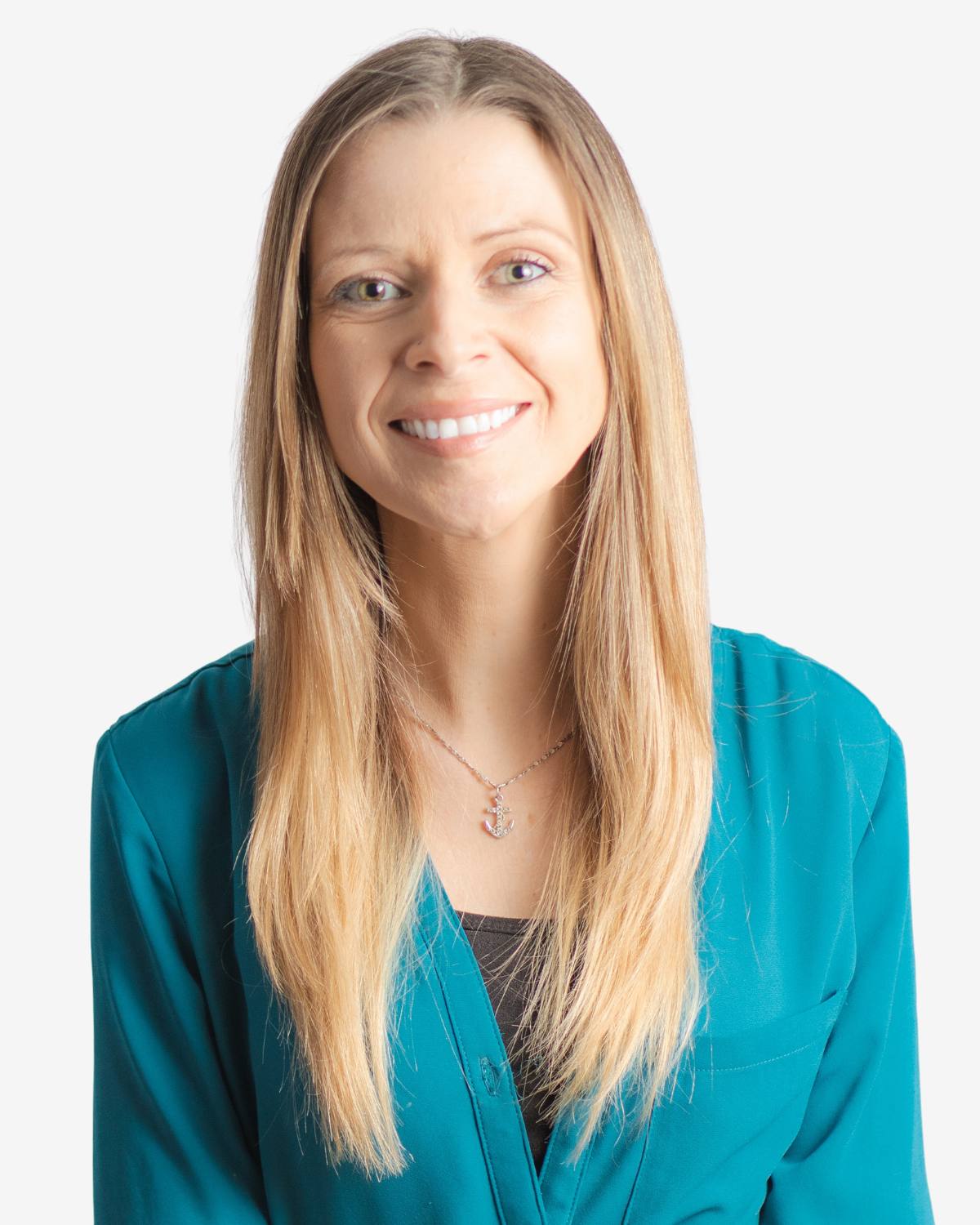 Woman in teal shirt with blonde hair smiling at camera.