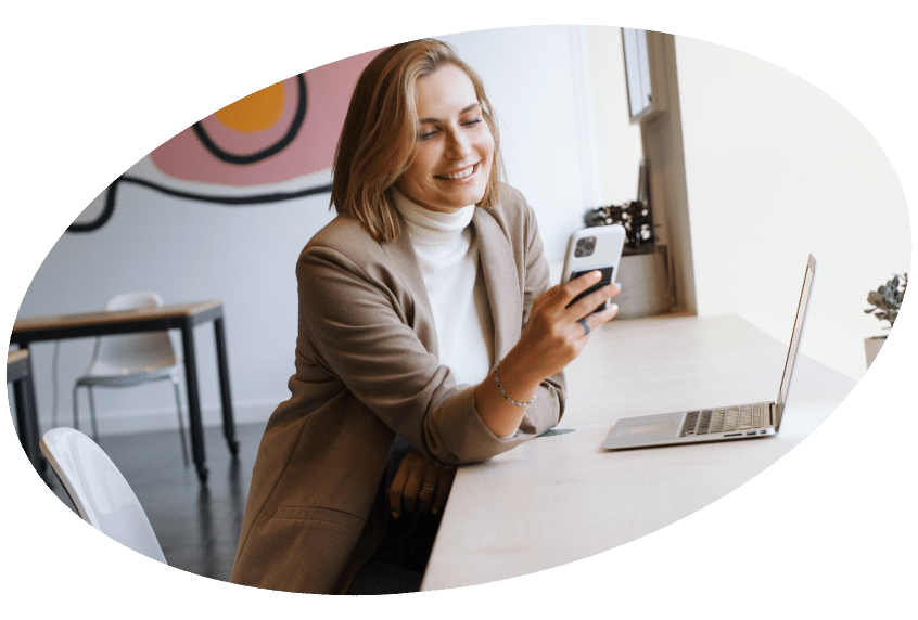 Woman using phone next to open laptop.